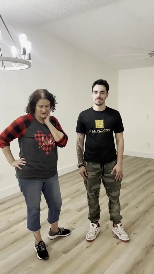 An Ozzifloors team member standing with a customer in an empty room on a newly installed wood-look plank floor