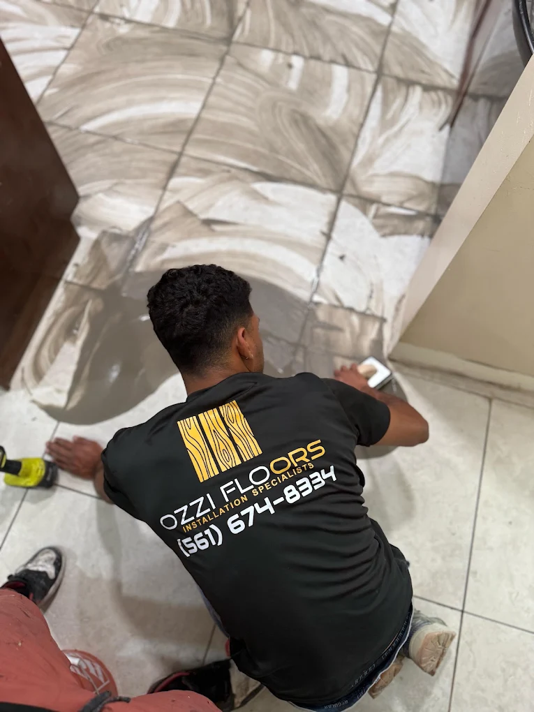 An Ozzifloors installer on his knees setting a large-format marble-look tile floor