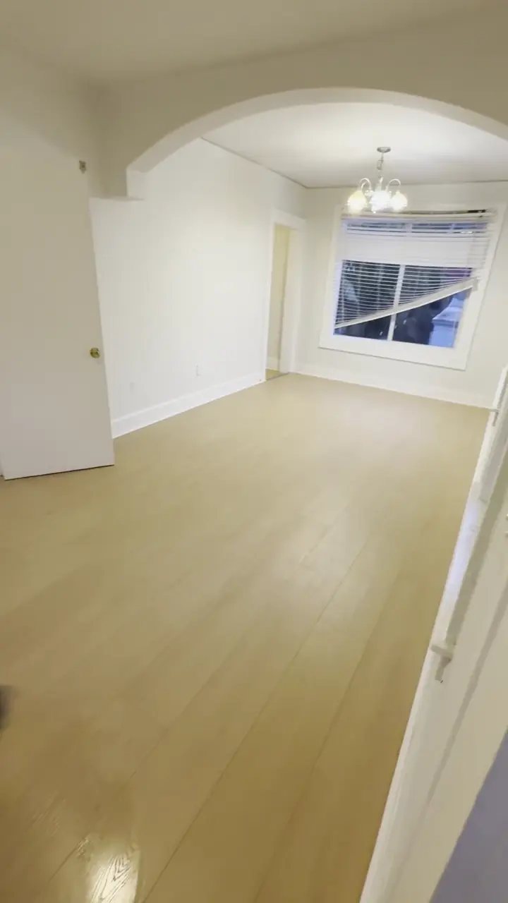 Honey Glaze laminate flooring installed by Ozzifloors in an empty room with an arched opening and a window